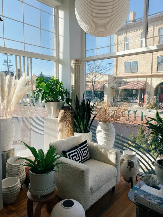A sunlit corner of the shop with a bouclé chair and paper lantern.