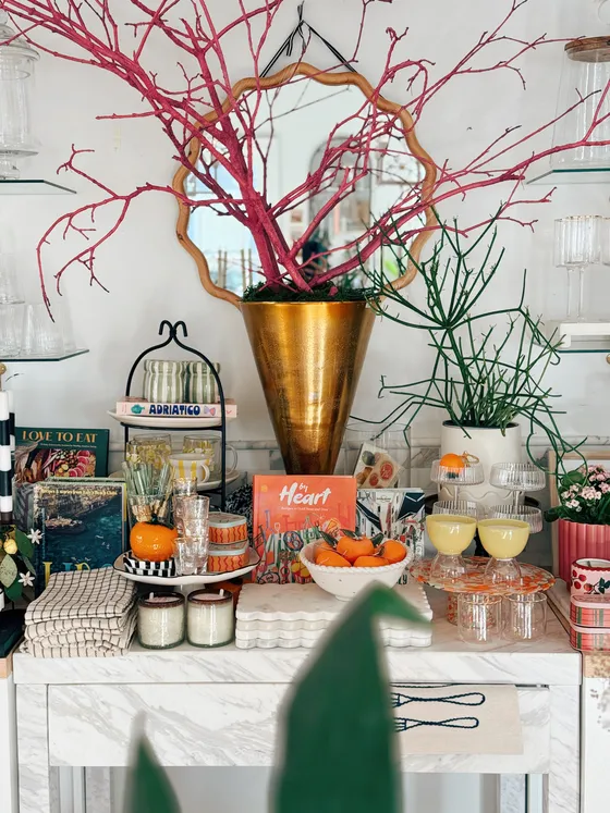 Marble console styled with cookbooks, coupe glasses, candle jars and a gold vase.