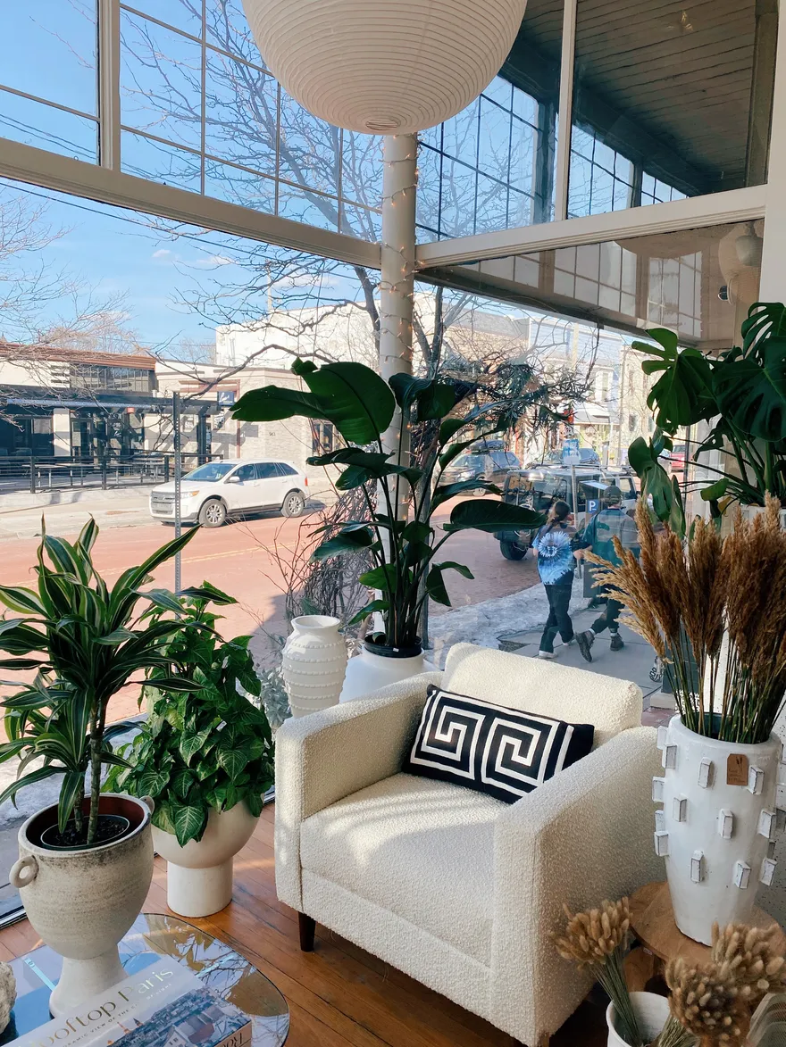 The window seat inside Commune: a bouclé chair, paper lantern and plants overlooking Cherry Street.